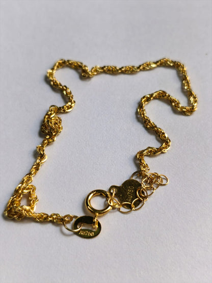 A gold chain necklace with a textured rope-style link design, featuring a lobster clasp, a heart-shaped tag, and a round oval tag engraved with '14K 925', displayed on a light gray background.